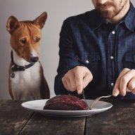 Man cuts piece of steak for his dog